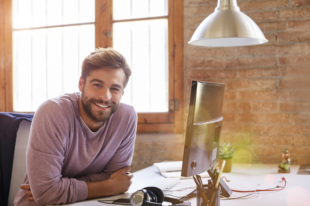 Confident businessman leaning on desk freiberufler am Schreibtisch