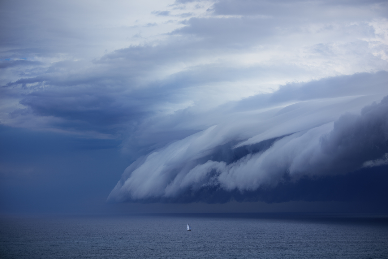 Tiny sailing boat and incoming supercell shelf cloud segelyacht im sturm