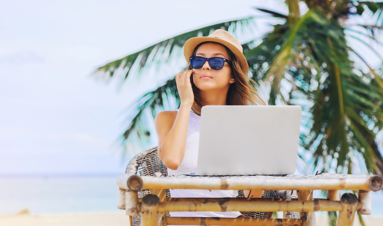 Digitalnomadin Frau mit Laptop am Strand
