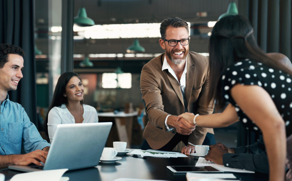 Business people meeting and handshake for partnership, b2b contract deal or woman inclusion promotion. Corporate team, manager shaking hands in office for commitment, onboarding or client negotiation Ein Mann berät drei Kunden am Tisch. Vermögensschadenhaftpflichtversicherung